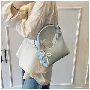 Detail of light blue patent leather hobo bag with pearl bow and silver heart pendant