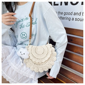Detail of hand-woven beige crochet saddle bag with brown leather strap and cloud charm