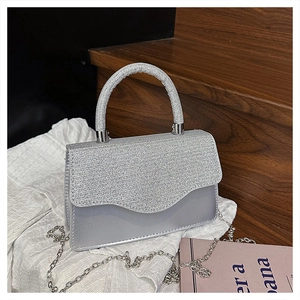 Détail d'un sac de soirée argenté à strass avec bandoulière sur bois rustique