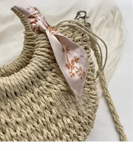 Detail of woven straw bag with floral silk scarf and metallic clasp on white fabric