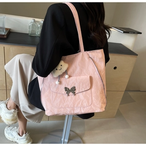 Detail of pink nylon tote bag with butterfly buckle front pocket and plush cloud charm