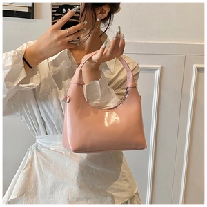 Detail of pink patent leather half-moon hobo bag with sleek finish and metal hardware