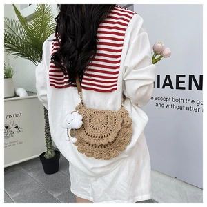 Detail of hand-woven straw saddle bag with cute cloud charm worn by a model