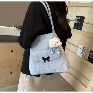 Close-up of light blue nylon tote bag with black bow buckle and plush cloud pendant