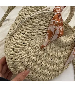 Detail showing the textured woven straw bag with a brown floral silk scarf handle