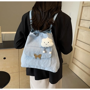 Close-up of light blue pleated tote bag with a golden butterfly buckle and cloud charm