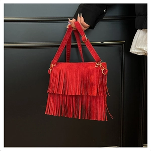 Détail du sac bandoulière bohème rouge à franges avec boucle dorée et texture en daim