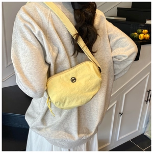 Model wearing a yellow nylon crescent crossbody bag with adjustable wide fabric strap