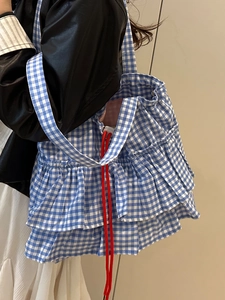 Sac cabas à carreaux bleu et blanc avec volants et cordons rouges porté par mannequin