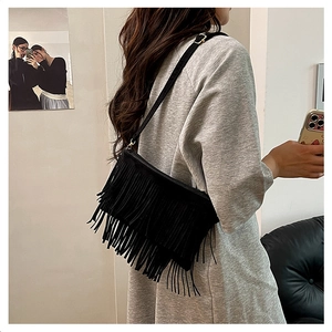 Détail d'un sac bandoulière bohème en daim noir avec franges porté par un mannequin