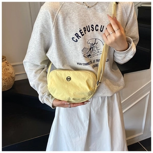 Detail of light yellow crescent shoulder bag with adjustable strap on model attire
