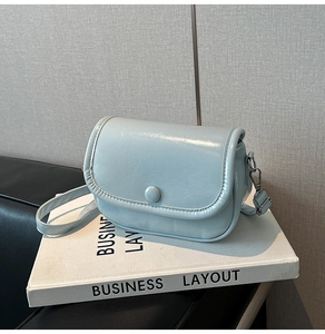 Detail of light blue crossbody bag with pleated texture and silver metal hardware accents