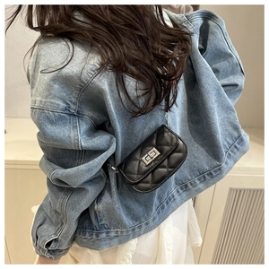 Detailed back view of a black quilted mini chain bag worn with casual denim and white dress