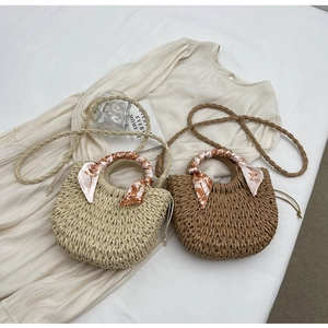 Detail of woven straw handbags featuring silk scarf handles and detachable straps