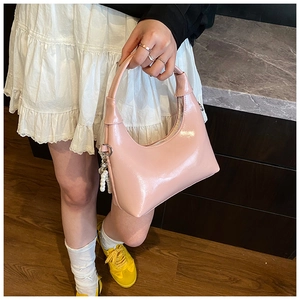 Close-up of pink patent leather hobo bag with pearl charm and silver zipper details