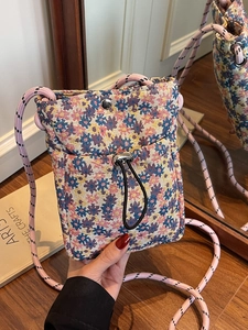 Floral jacquard small crossbody phone bag with pink rope strap shown in hand reflexively