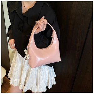 Detail of pink patent leather hobo bag with glossy finish and pearl charm accessory