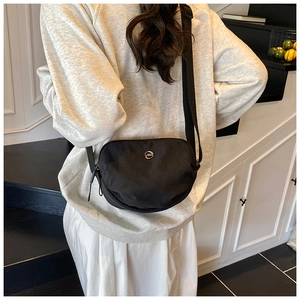 Detail of minimalist black nylon crossbody bag with circular JZD logo on adjustable strap