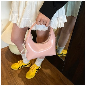 Detail of pink patent leather half-moon shoulder bag with a decorative pearl charm