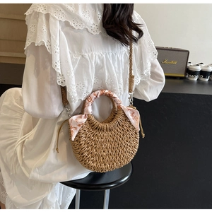 Close-up of woven straw bag with floral scarf handle in a cozy lifestyle setting