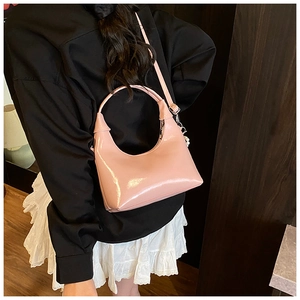 Pink glossy hobo bag with pearl charm shown as a shoulder bag on a model side view
