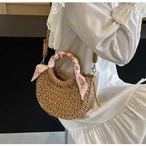 Detail of woven straw bag featuring floral scarf handle and detachable shoulder strap