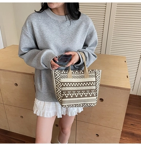 Detail of canvas tote bag with geometric stripe pattern held by model in casual outfit