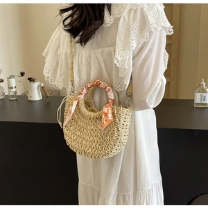 Detail of woven straw basket bag with orange printed silk scarf handle and drawstring