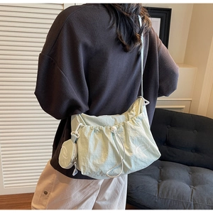 Detail view of light green pleated crossbody bag with white drawstring and mini coin purse