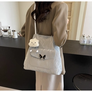Detail of light gray pleated tote bag featuring silver butterfly buckle and cloud charm