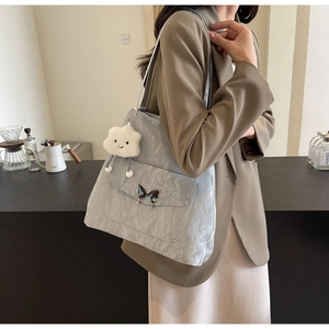 Detail of grey tote bag with butterfly buckle and cute plush charm on shoulder
