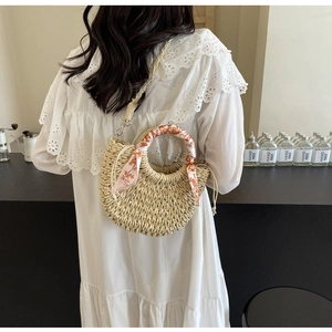 Detail of woven straw handbag with floral silk scarf on handle and drawstring closure