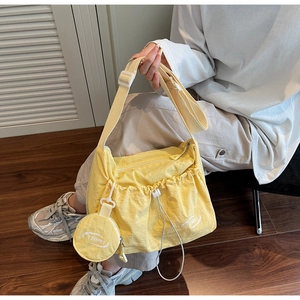 Close-up of cream nylon crossbody bag featuring drawstring folds and a mini coin purse