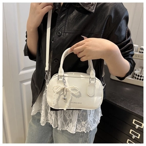 Dettaglio della mini borsa a mano bianca con fiocco di perle e stampa di tendenza