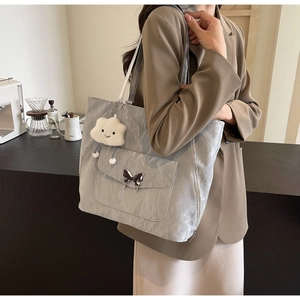 Detail of grey tote bag with pleated texture, butterfly buckle and cloud charm