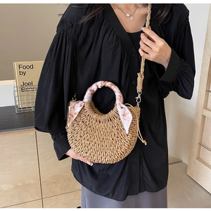 Detail of woven crescent bag featuring silk scarf handle and detachable long shoulder strap