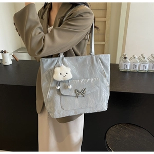 Detail of light gray pleated tote bag with silver butterfly buckle and cloud charm