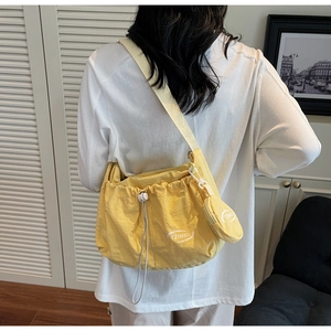 Detail of bright yellow nylon crossbody bag with drawstring closure and coin pouch