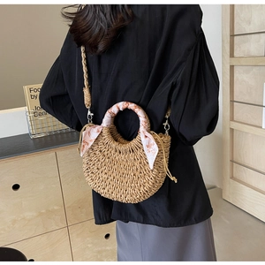Detail of woven straw crossbody bag with floral scarf handle and drawstring closure