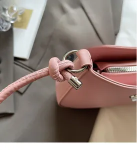 Detail of premium light pink leather texture and silver metal hardware on a shoulder bag