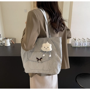 Detail of silver tote bag featuring pleated texture, butterfly buckle and cloud charm