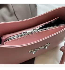 Detail of a pink leather handbag with smooth silver zipper and metal bow accent