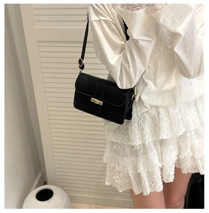 Close-up of black faux crocodile skin pattern and golden metal lock on handbag