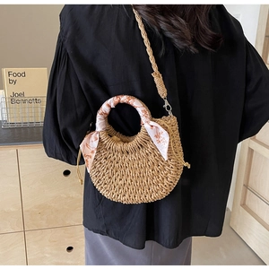 Detail of hand-woven straw hobo bag with floral scarf handle and wide shoulder strap