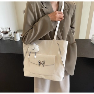 Detailed shot of beige tote bag with silver butterfly buckle and side zipper accents