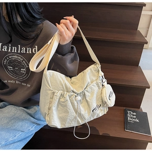 Detail of off-white nylon tote bag with drawstring texture and small round coin purse