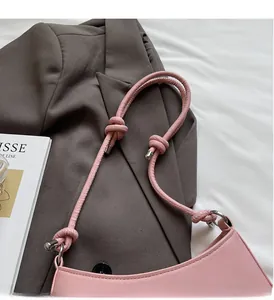 Detail of soft pink crescent bag with knotted shoulder strap and silver metal accents