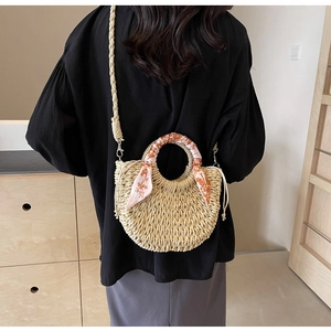 Detail of woven straw crossbody bag with floral silk scarf handle and drawstring closure