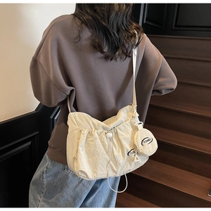 Close-up of cream nylon crossbody bag with drawstring ruffles and round coin purse detail