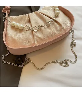 Detail of light pink pleated cloud bag with pearl chain and floral metal hardware